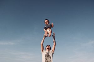 photo of man throwing up baby in air
